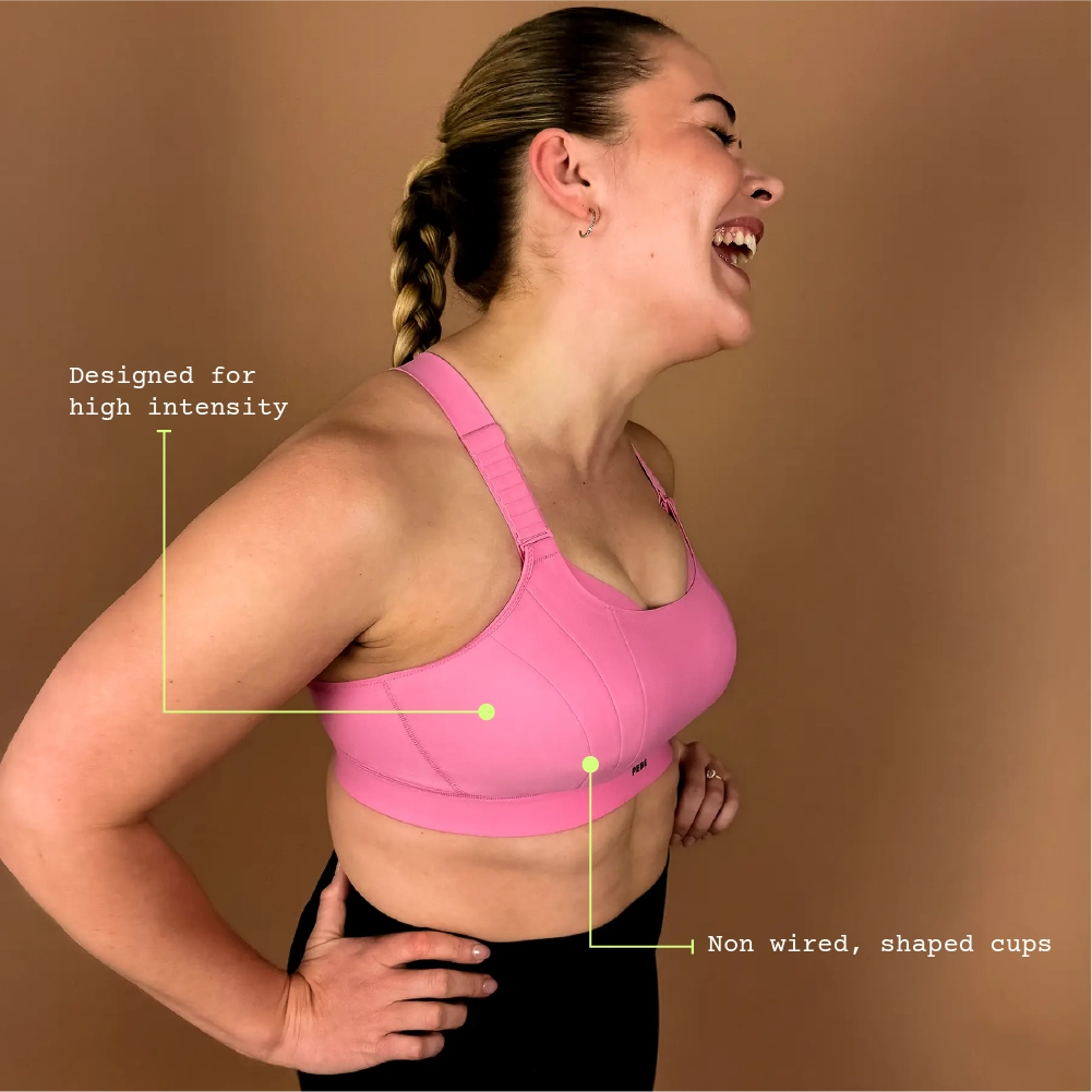 Side view of pink Gravity high impact sports bra with adjustable straps, supportive fit, hands on hips pose.
