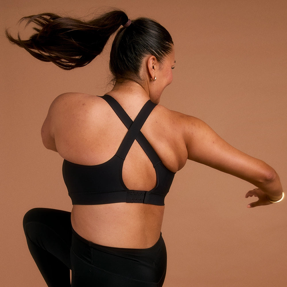 Woman in black cross-back sports bra lifting knee in active pose