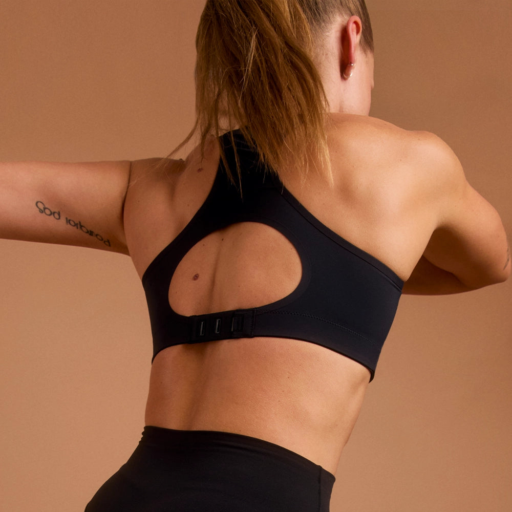 Back view of woman in black racerback sports bra with clasp closure.