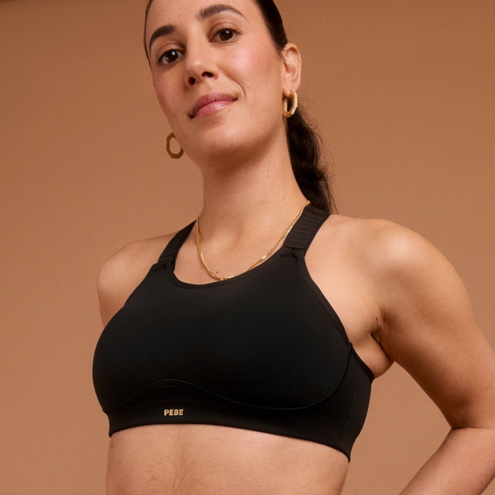 Confident woman wearing black high-support sports bra with PEBE logo