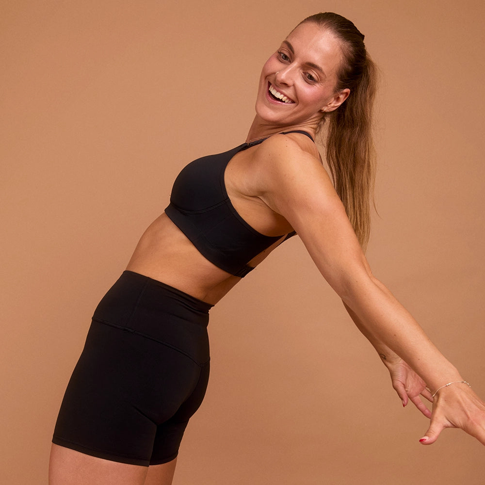 Smiling woman in black sports bra and shorts for high-impact workouts