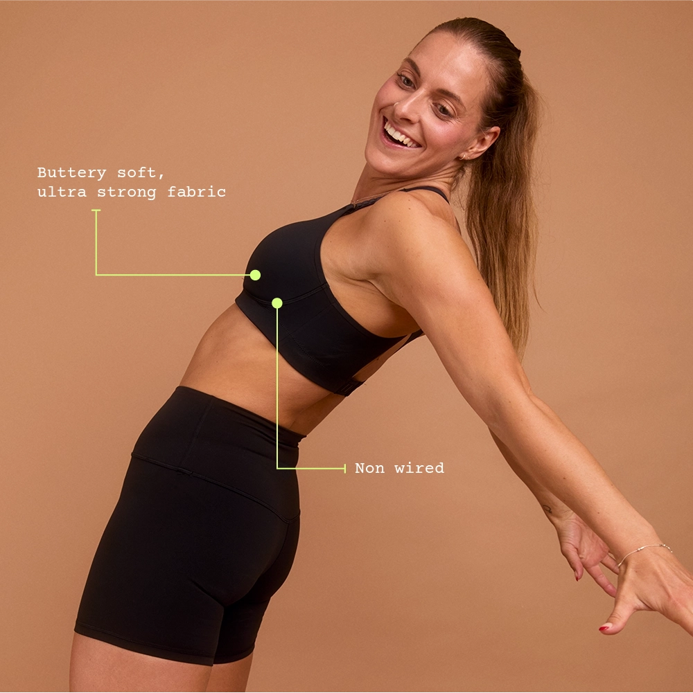 Smiling woman in black sports bra and shorts for high-impact workouts