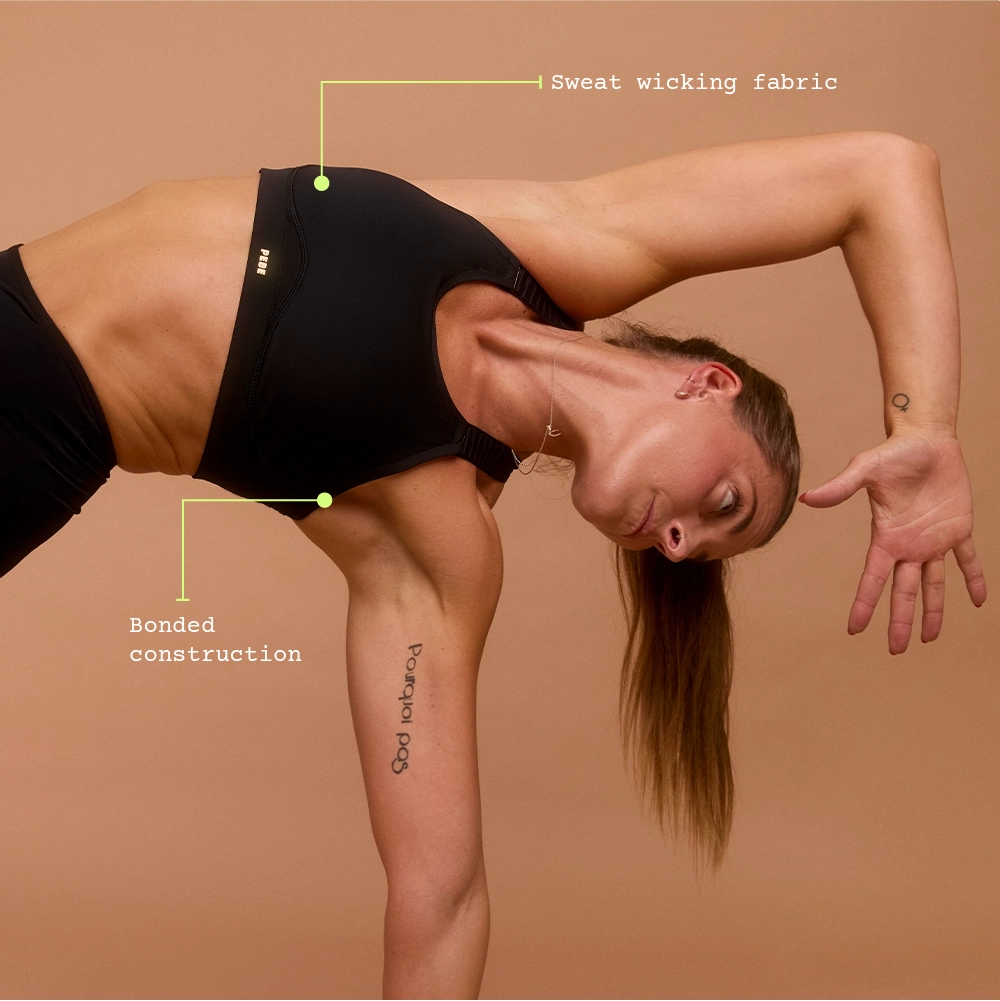 Woman stretching in black medium-impact sports bra for hyrox training