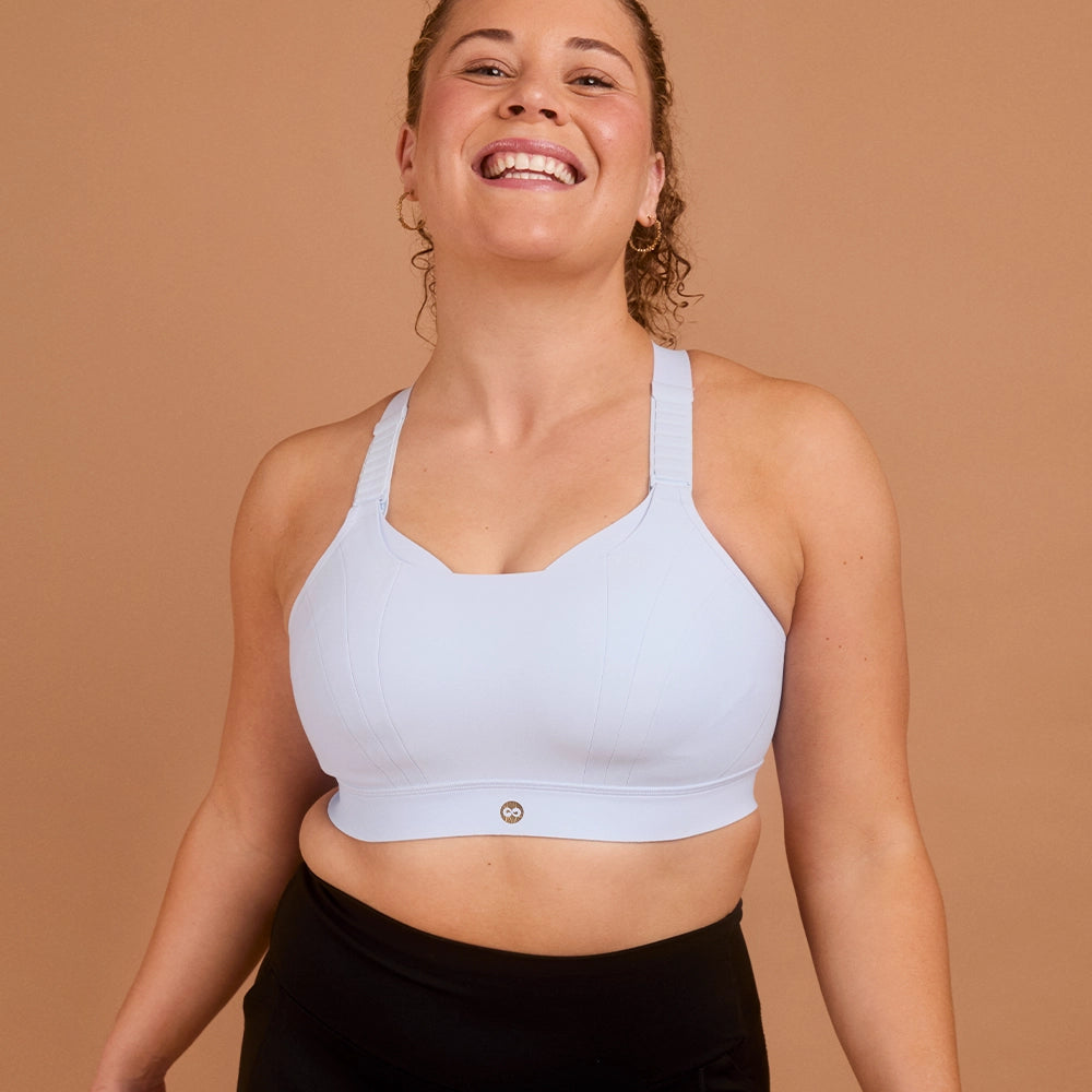 Smiling woman wearing light blue high impact sports bra for large cup size