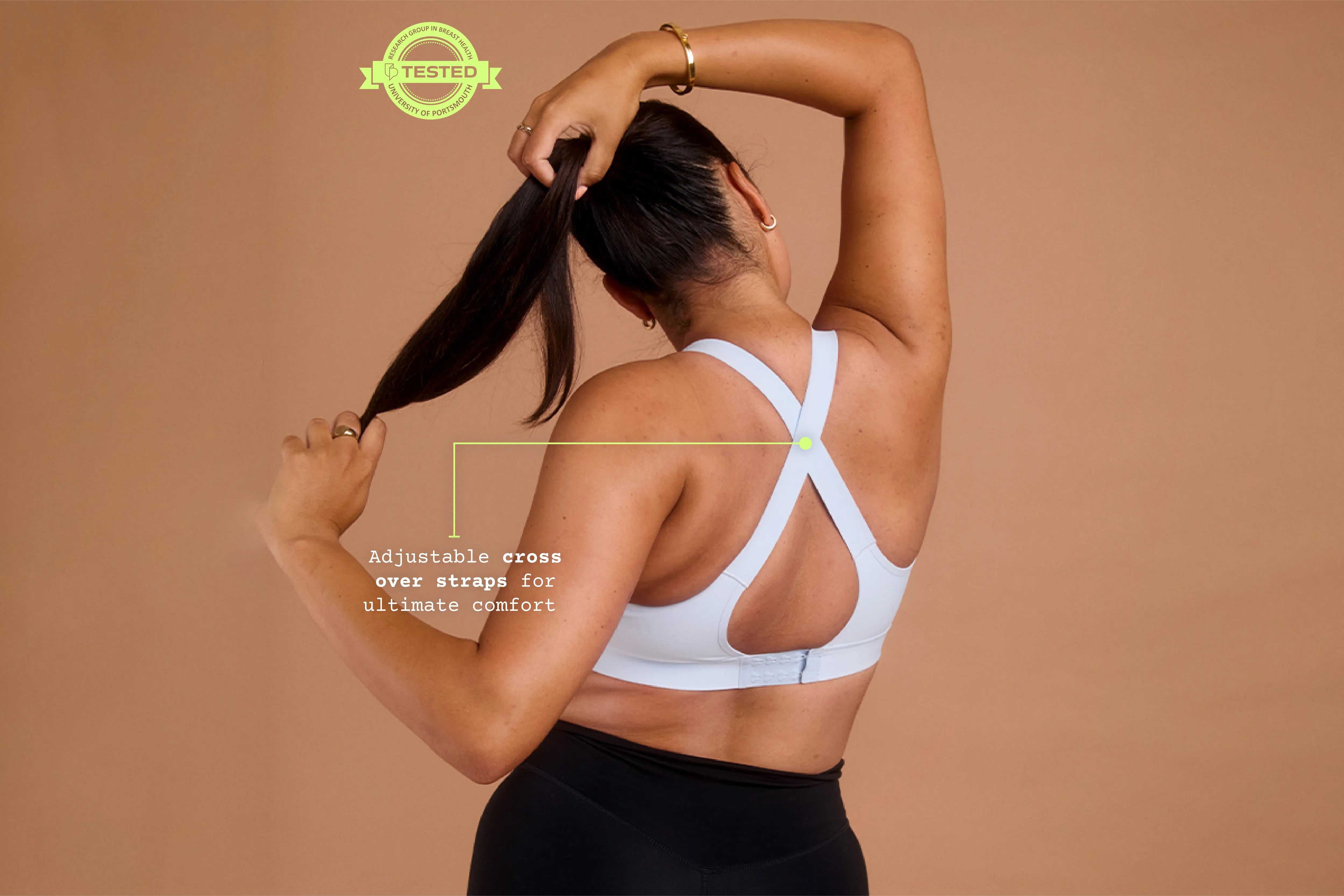 Back view of model wearing blue Gravity sports bra with adjustable cross back straps.