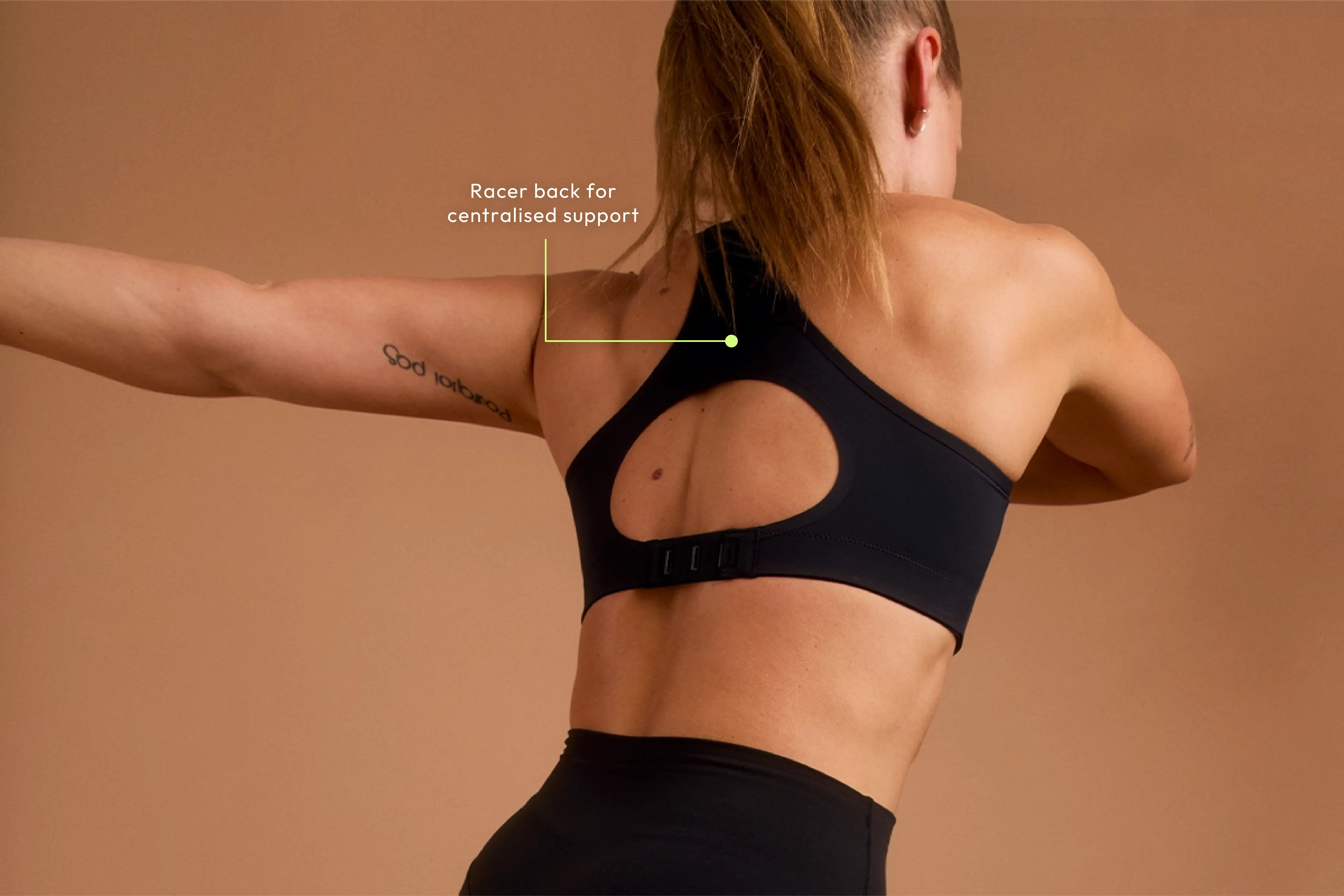 Woman stretching in black sports bra with racer back and centralised support feature.