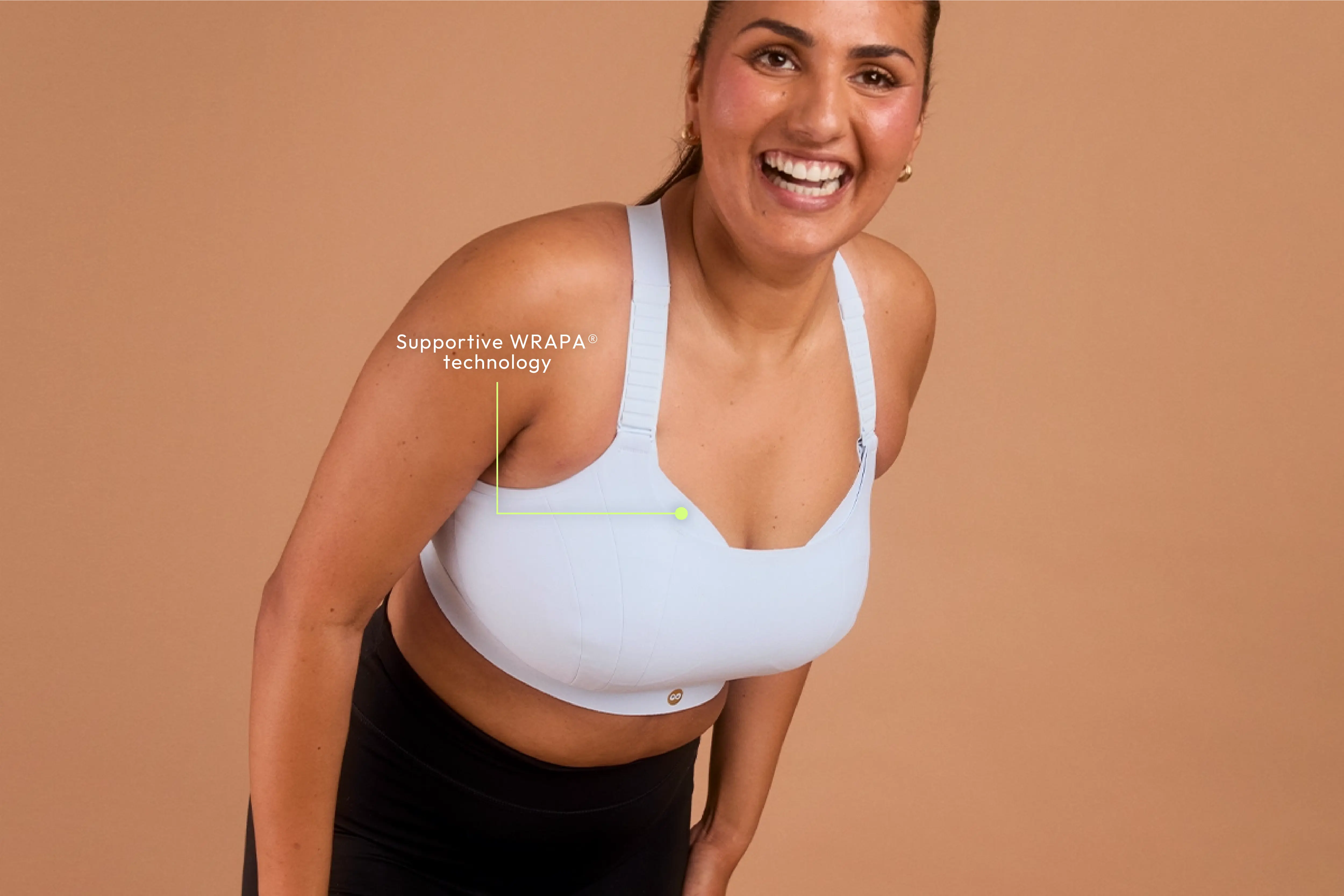 Woman leaning forward in blue sports bra featuring PEBE WRAPA® support technology.