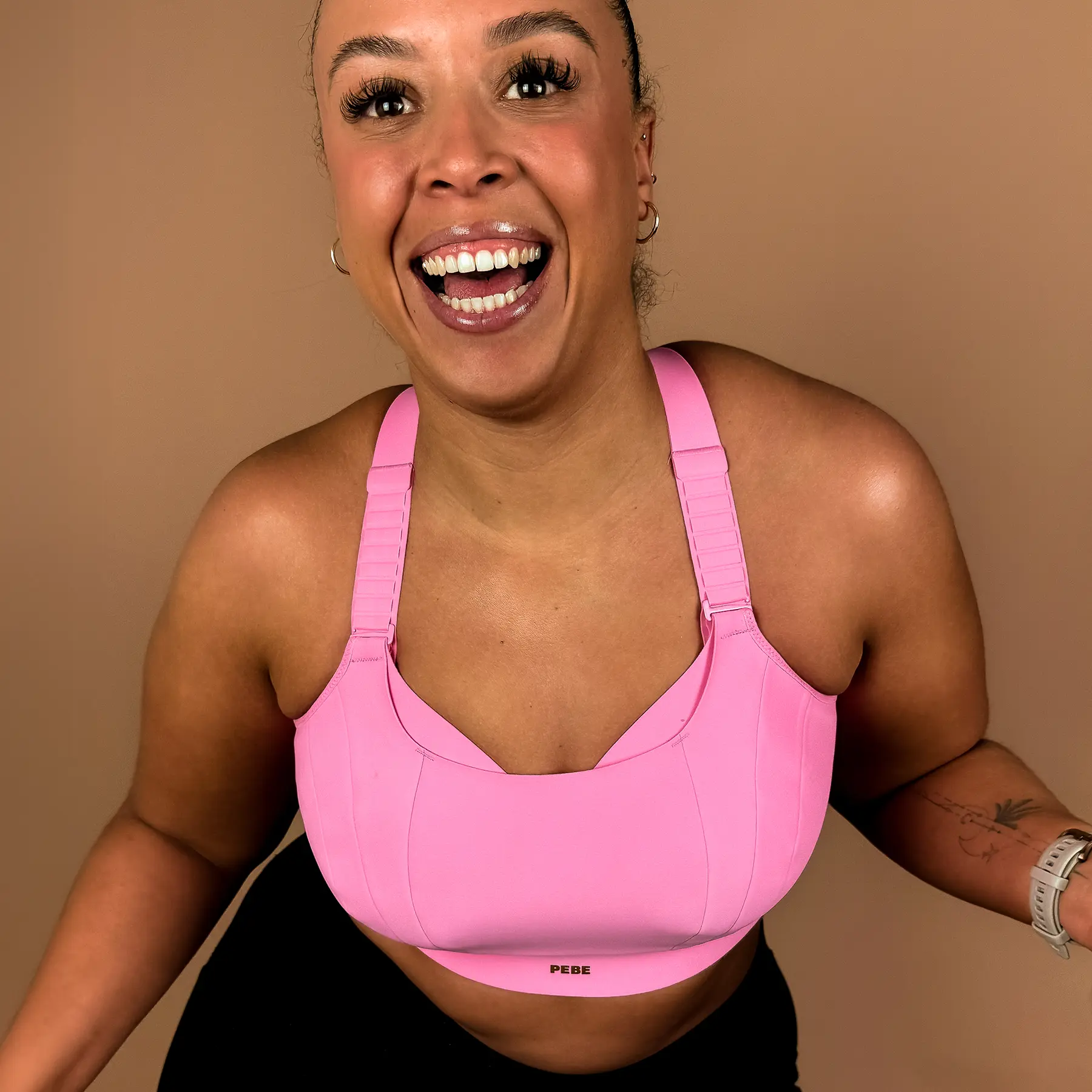 Woman wearing PEBE Gravity high impact pink sports bra with adjustable straps, front view.