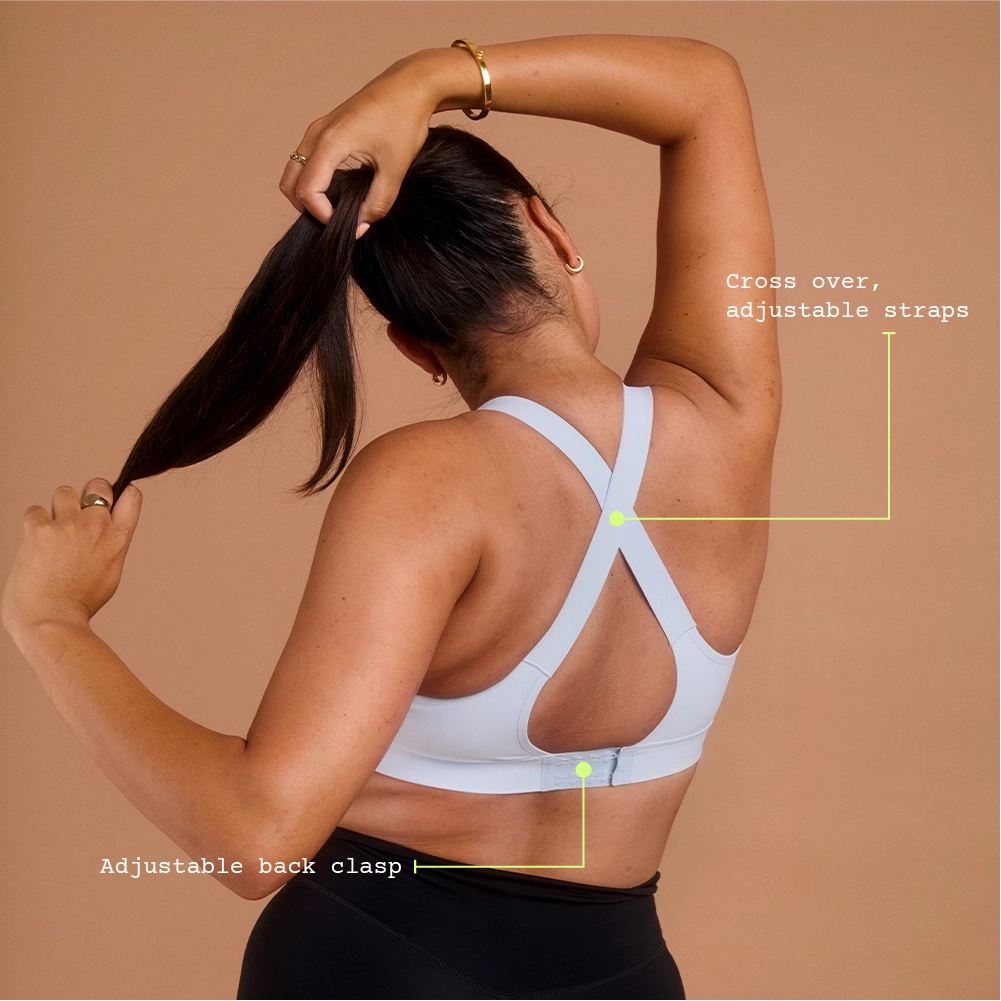 Woman in light blue cross-back sports bra holding her ponytail