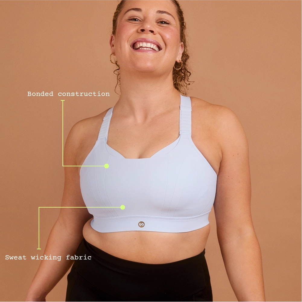 Smiling woman wearing light blue high impact sports bra for large cup size